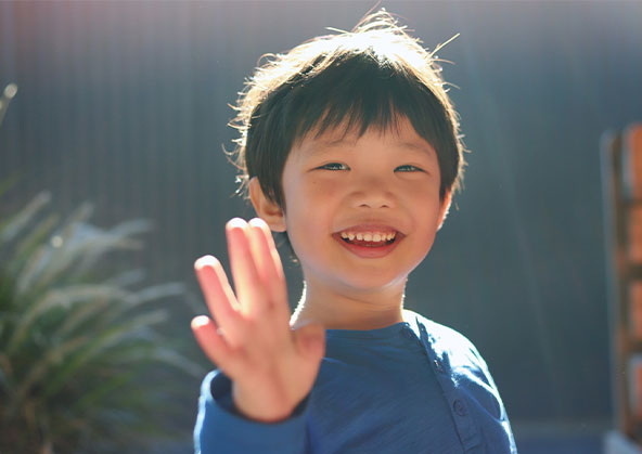 A five year old Asian boy waving