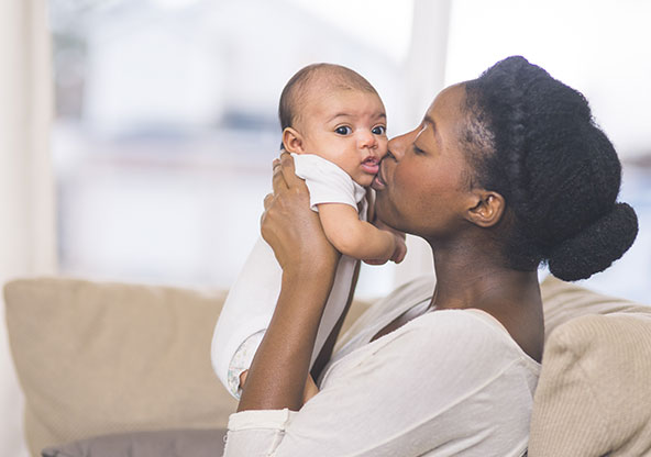 Black mother kissing baby