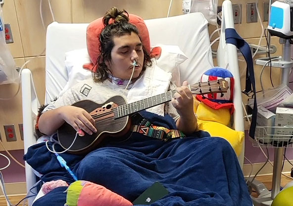 boy playing guitar in hospital bed