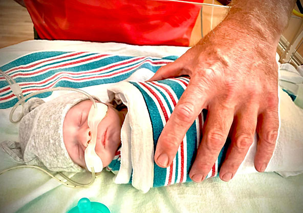 newborn Beau with dads hand for scale