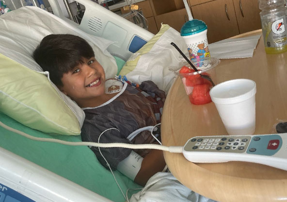 Emmitt Garza smiling in his hospital bed after his aortic coarctation surgery