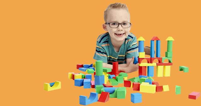 Young, happy boy playing with colorful building blocks