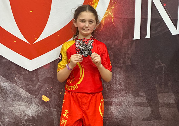 young girl holding up medal