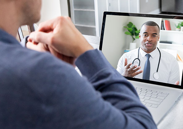 A man at work doing an On Demand Care virtual urgent care visit with a provider. He is getting treated virtually through On Demand Care for a sinus infection.