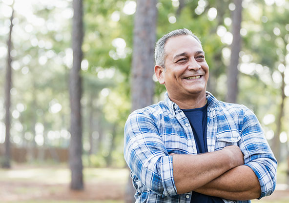50 year old Hispanic man crossing his arms and smiling outside