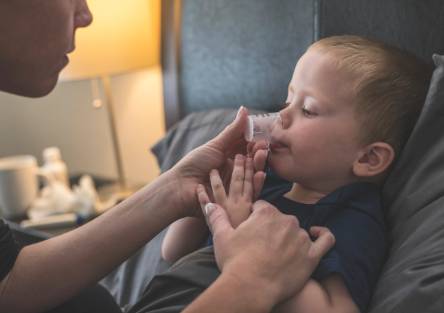 A parent gives medicine to a toddler
