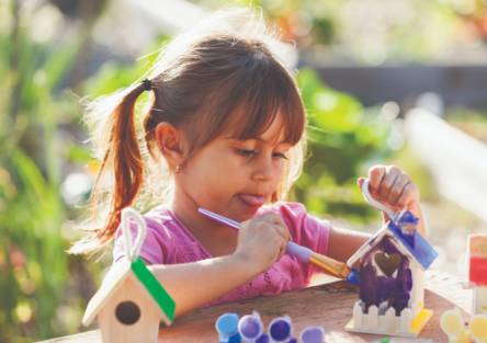 A girl paints a birdhouse