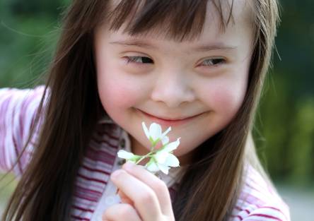 A girl holding a flower and smiling