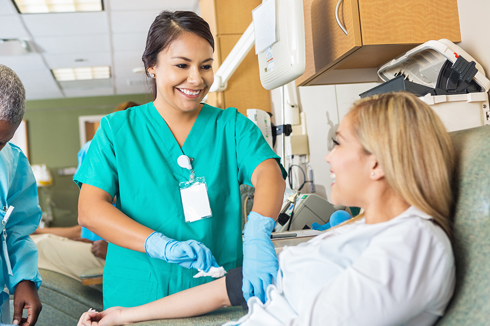 Nurse bandaging arm after patient donates blood in hospital bank