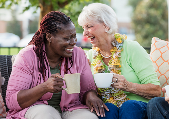 Two elderly women laughing and drinking coffee