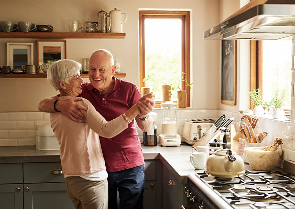 Elderly white couple dancing in the kitchen