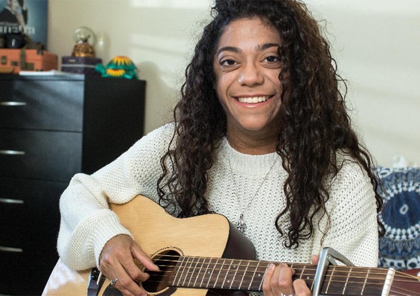 Allorah Cota smiling with her guitar in her hand.