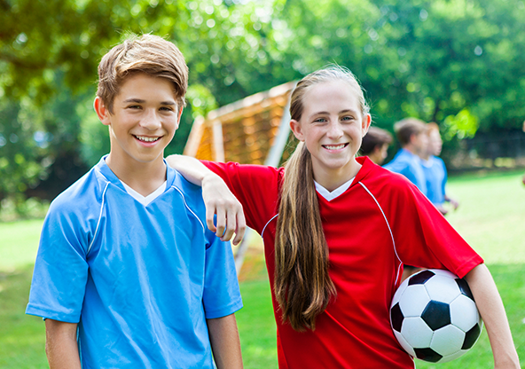 A boy and a girl smiling at their soccer game
