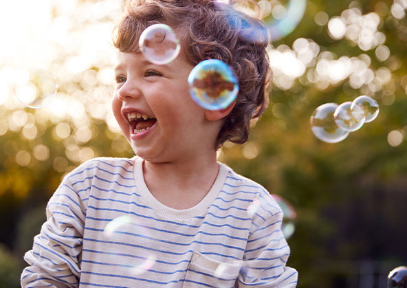 A young boy playing with bubbles outside