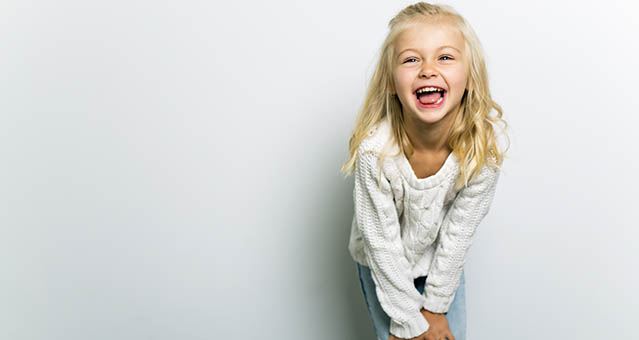 Blonde little girl looking into the camera laughing