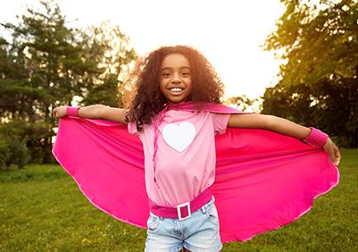 Girl smiling in a cape outdoors