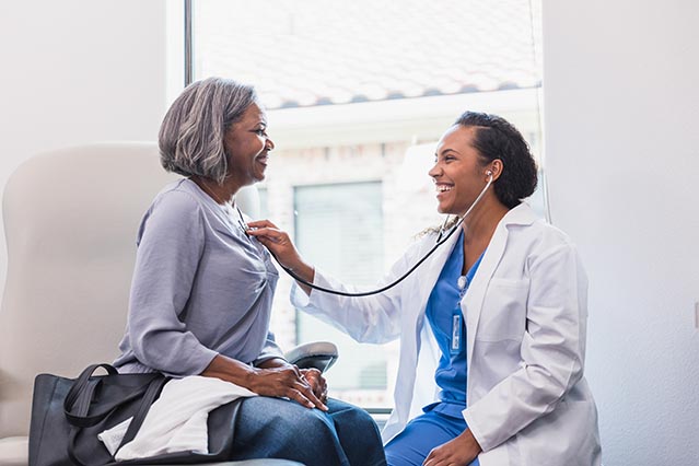 Young African American female doctor examining older African American woman