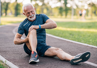 Man holding his knee in pain on a running track.