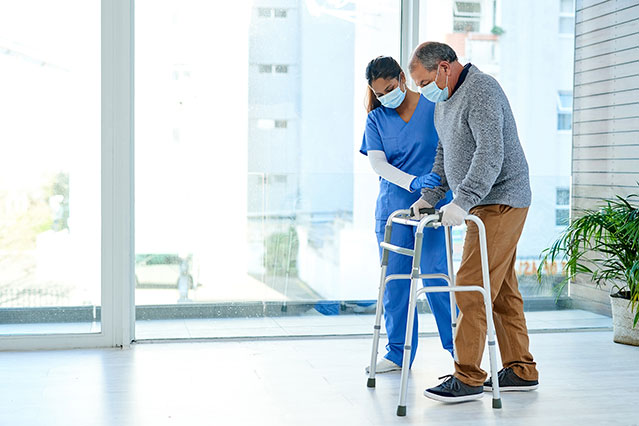 Nurse helping man walk with a walker