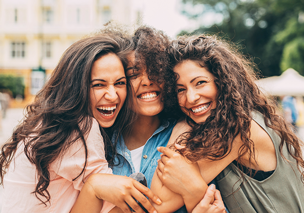 Three women smiling and hugging each other
