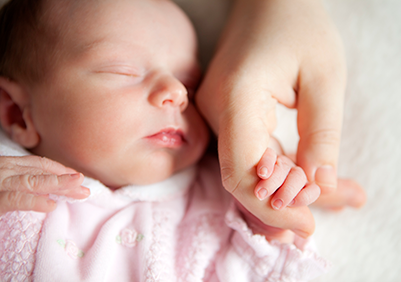 A baby holding their parents finger