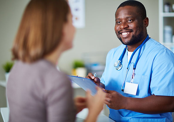 Male nurse talking to a patient and writing things down on a clipboard at an urgent care