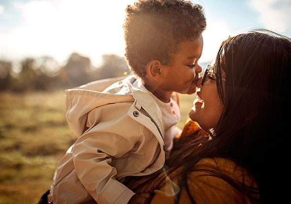 A mom holds her young son up outside