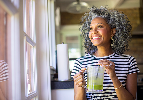 An African American female drinking a green juice
