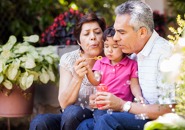 Grandparents blowing bubbles with their granddaughter