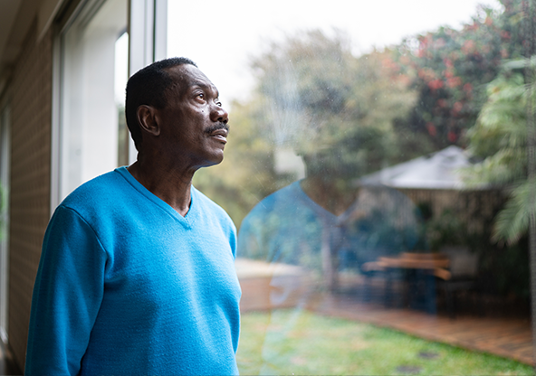 A senior black man staring out the window
